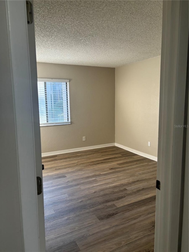 unfurnished room with a textured ceiling and dark hardwood / wood-style floors