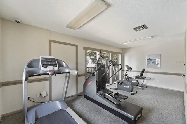 exercise room with a textured ceiling and carpet