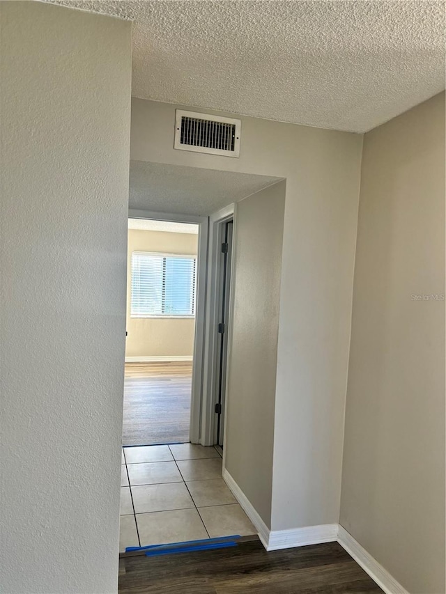 hall with tile patterned floors and a textured ceiling