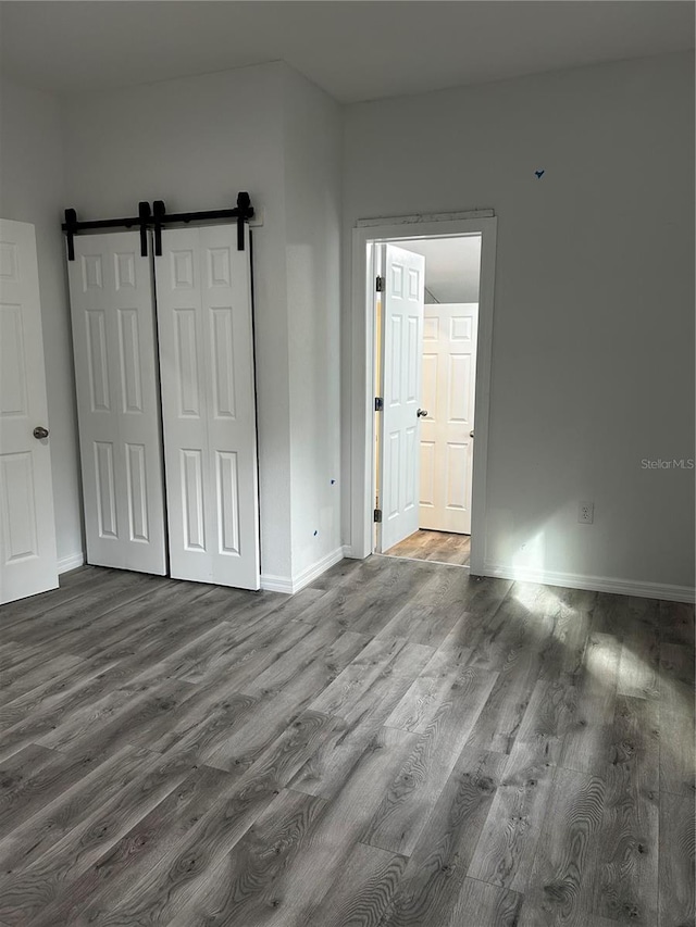 unfurnished bedroom featuring hardwood / wood-style flooring and a barn door