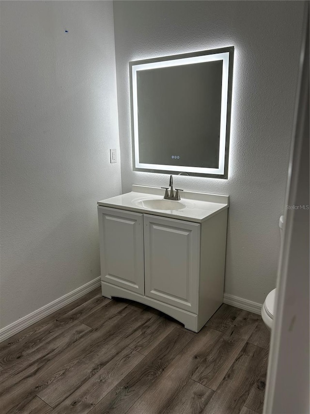 bathroom with hardwood / wood-style floors, vanity, and toilet