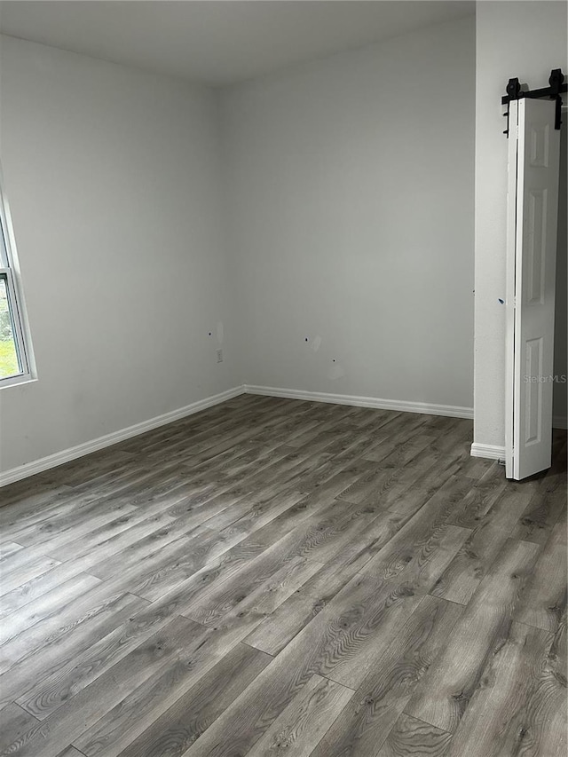 unfurnished room featuring a barn door and hardwood / wood-style flooring