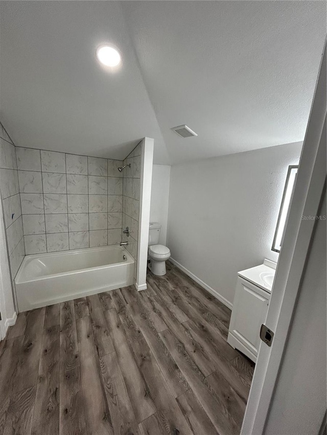 full bathroom with hardwood / wood-style floors, tiled shower / bath combo, toilet, and vanity