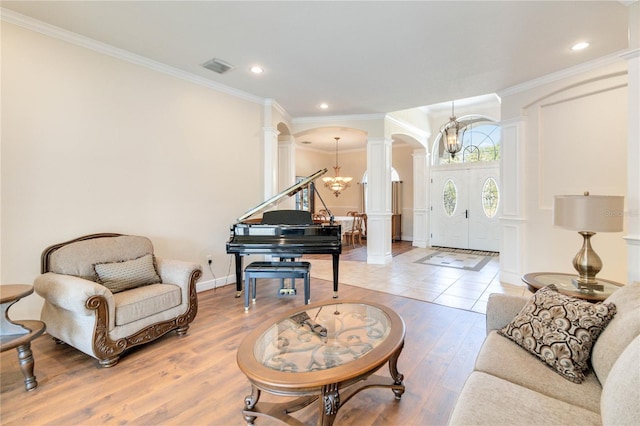 living room with an inviting chandelier, hardwood / wood-style flooring, ornate columns, and ornamental molding