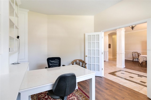 office area featuring ornate columns, hardwood / wood-style floors, and lofted ceiling