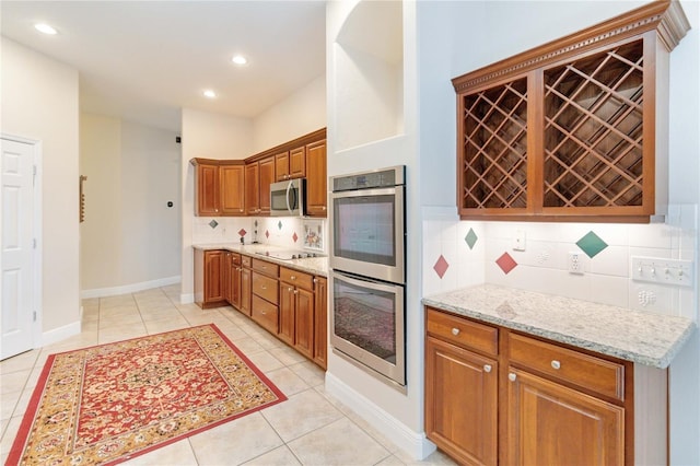 kitchen with light stone countertops, backsplash, stainless steel appliances, and light tile patterned flooring