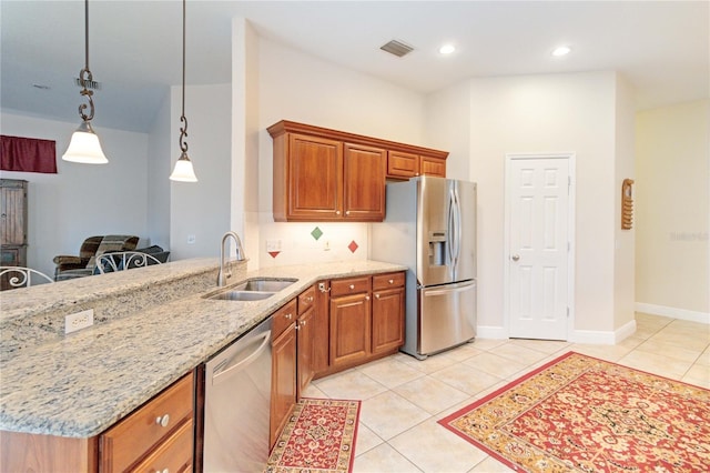 kitchen with hanging light fixtures, sink, light stone countertops, appliances with stainless steel finishes, and kitchen peninsula