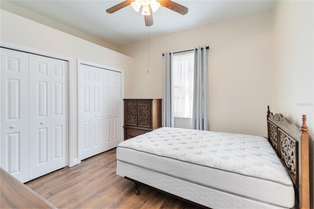 bedroom featuring ceiling fan, dark wood-type flooring, and two closets