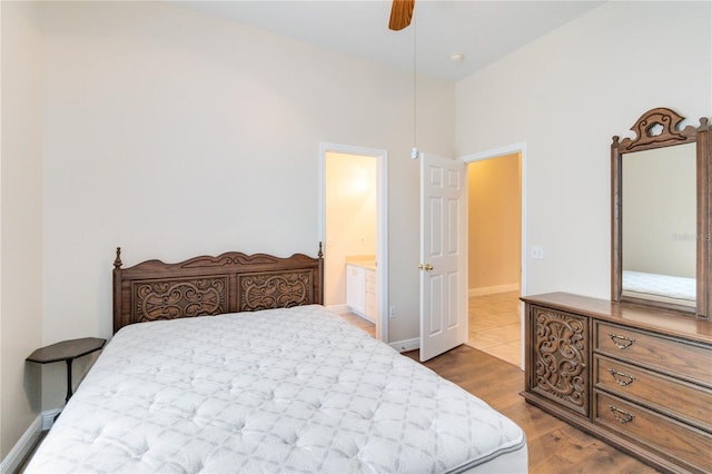 bedroom featuring hardwood / wood-style floors, a towering ceiling, ceiling fan, and connected bathroom