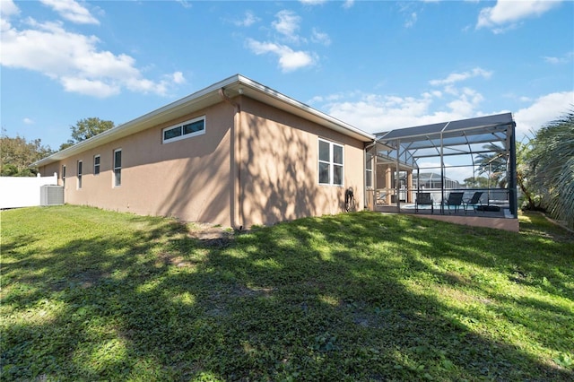 rear view of house featuring a lawn, a lanai, and central air condition unit