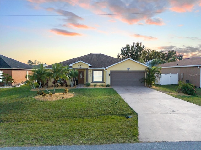 ranch-style home featuring a garage and a lawn