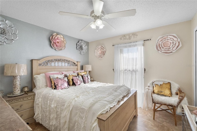 bedroom featuring ceiling fan, light tile patterned floors, and a textured ceiling