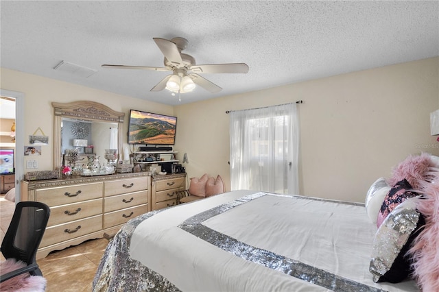 bedroom featuring a textured ceiling, ceiling fan, and light tile patterned flooring