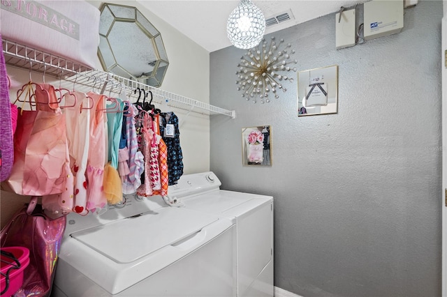 clothes washing area with washing machine and dryer and an inviting chandelier