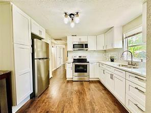 kitchen with stainless steel appliances, white cabinetry, and dark wood-type flooring