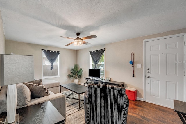 living room with a textured ceiling, dark hardwood / wood-style flooring, and ceiling fan