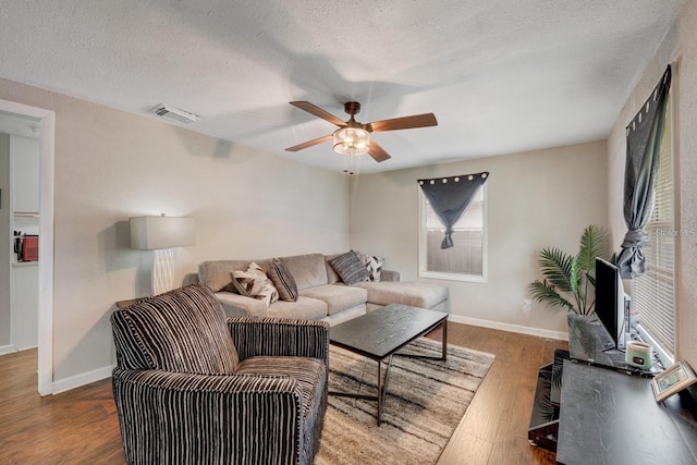 living room featuring ceiling fan, hardwood / wood-style floors, and a textured ceiling