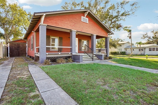 view of front facade featuring a front yard, a porch, and a storage unit