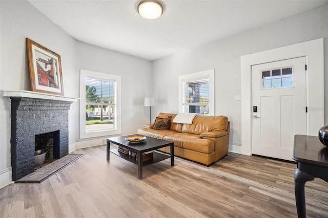 living room featuring light wood-type flooring and a stone fireplace