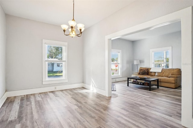 unfurnished room with light hardwood / wood-style floors, an inviting chandelier, and a healthy amount of sunlight