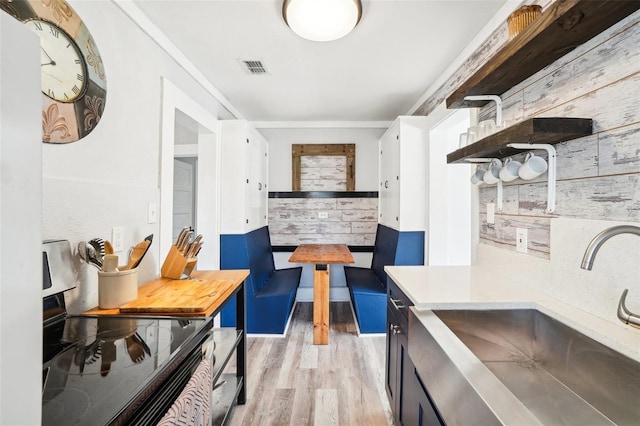 kitchen featuring sink, electric range oven, light hardwood / wood-style flooring, white cabinets, and ornamental molding