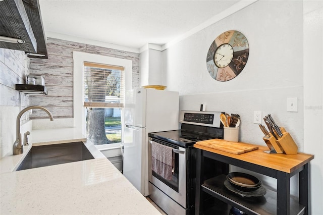 kitchen with wooden counters, stainless steel range with electric stovetop, crown molding, sink, and white fridge