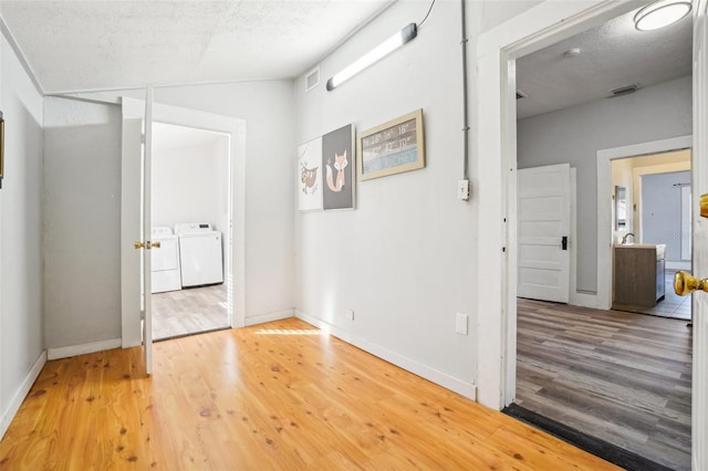 hallway with washer and dryer, hardwood / wood-style floors, a textured ceiling, and vaulted ceiling