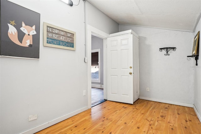 interior space with hardwood / wood-style floors, a textured ceiling, and vaulted ceiling