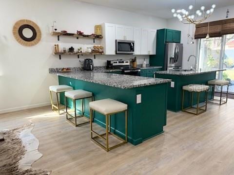 kitchen featuring a kitchen breakfast bar, kitchen peninsula, stainless steel appliances, and light hardwood / wood-style floors