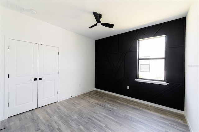 unfurnished bedroom featuring light wood-type flooring, a closet, and ceiling fan