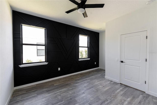 unfurnished room with ceiling fan, wood-type flooring, and a textured ceiling