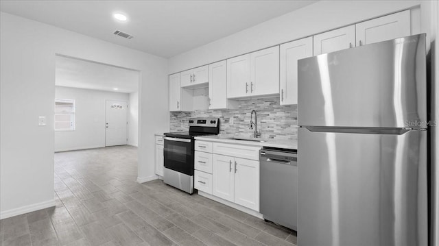 kitchen with tasteful backsplash, stainless steel appliances, sink, light hardwood / wood-style floors, and white cabinetry