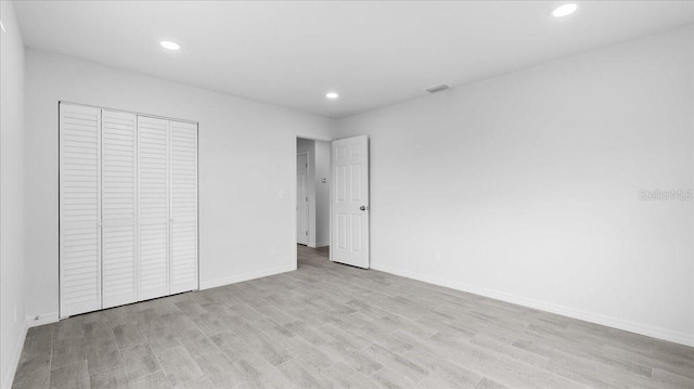 unfurnished bedroom with light wood-type flooring and a closet