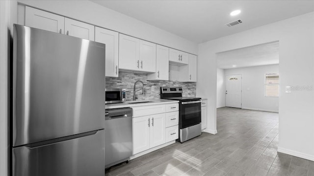 kitchen with white cabinets, appliances with stainless steel finishes, light hardwood / wood-style flooring, and sink