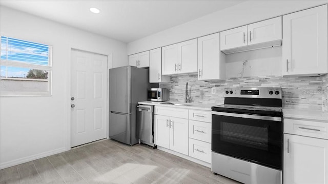 kitchen with decorative backsplash, appliances with stainless steel finishes, white cabinetry, and sink