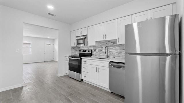 kitchen with white cabinets, stainless steel appliances, light hardwood / wood-style floors, and sink