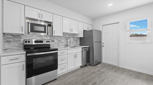 kitchen with stainless steel appliances, white cabinetry, and sink