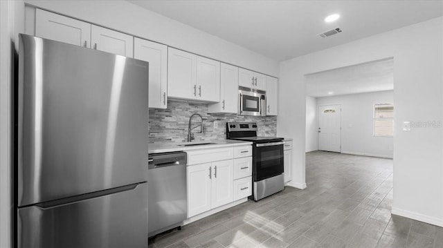 kitchen featuring white cabinetry, sink, light hardwood / wood-style flooring, and appliances with stainless steel finishes