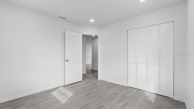 unfurnished bedroom with a closet and light hardwood / wood-style flooring