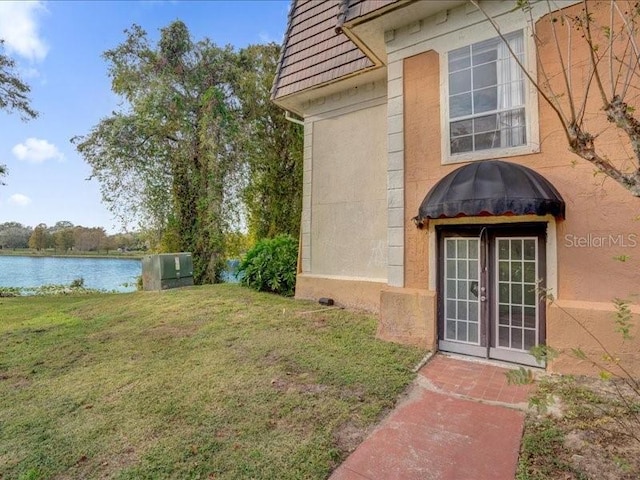 entrance to property with a yard, french doors, and a water view