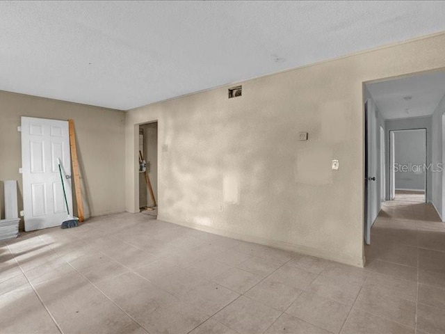 tiled spare room with a textured ceiling