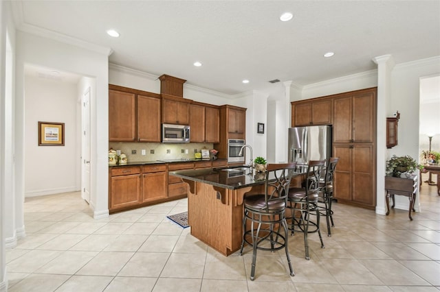 kitchen featuring backsplash, a kitchen island with sink, a kitchen breakfast bar, sink, and appliances with stainless steel finishes