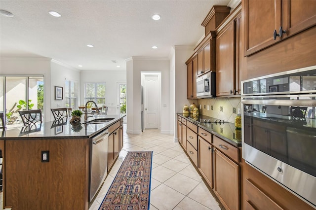 kitchen with ornamental molding, sink, an island with sink, and stainless steel appliances