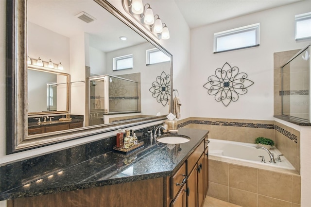 bathroom featuring plus walk in shower, vanity, and plenty of natural light