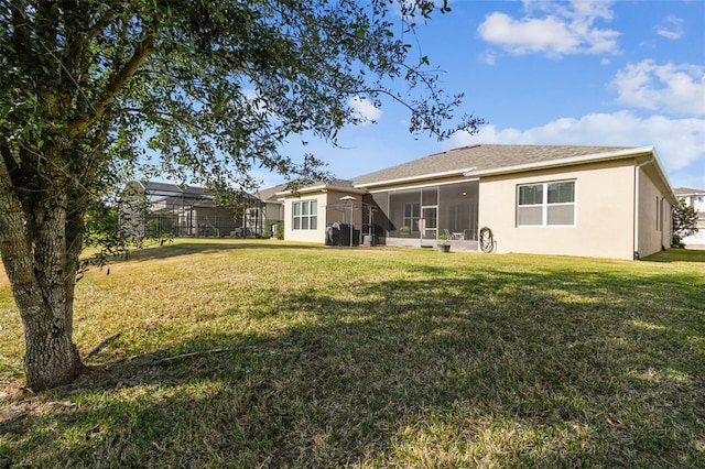 rear view of house with a yard, a lanai, and a sunroom