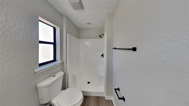 bathroom with a shower, a textured ceiling, hardwood / wood-style flooring, and toilet