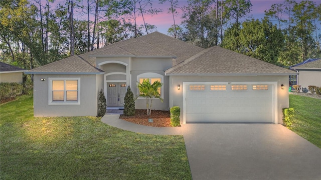 ranch-style home featuring a garage, a front yard, concrete driveway, and a shingled roof