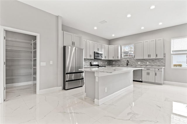 kitchen with white cabinets, appliances with stainless steel finishes, backsplash, and a kitchen island