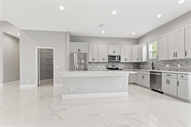 kitchen with backsplash, stainless steel appliances, a kitchen island, and white cabinetry