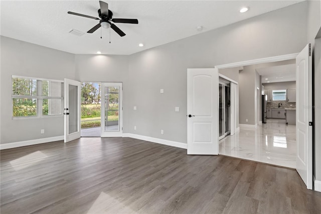 unfurnished room with ceiling fan, hardwood / wood-style floors, a healthy amount of sunlight, and a textured ceiling